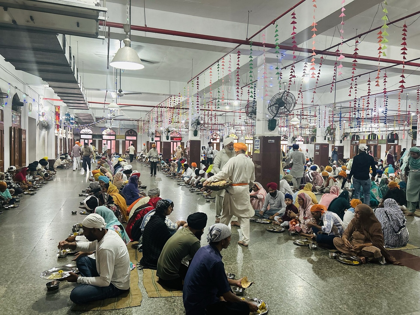 People sitting in rows eating langar at the Golden Temple